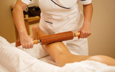 Unrecognizable woman during maderotherapy at the spa. Unrecognizable therapist performing maderotherapy on woman's legs during massage treatment at the spa.